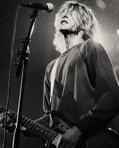 a woman with blonde hair playing guitar in front of a microphone and singing into a mic