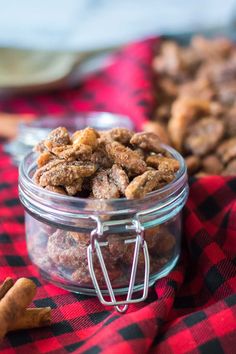 a glass jar filled with nuts on top of a red and black checkered table cloth