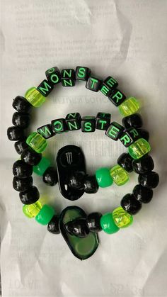 two black and green bracelets with the word monsters written on them, one is made out of plastic beads