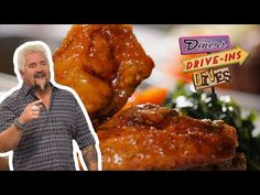 a man standing in front of a pile of chicken wings on top of a table