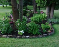 a flower garden in the middle of a park with trees and flowers growing around it