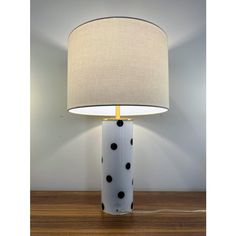 a table lamp with a white and black polka dot design on it, sitting on a wooden floor