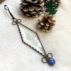 pine cones and scissors are sitting next to each other on a white counter top with an old mirror hanging from it