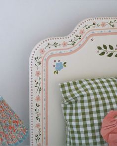 a white bed topped with pillows next to a night stand and table cloth on top of it