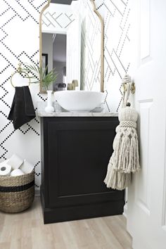 a bathroom with black and white wallpaper, a sink and mirror