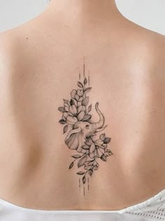 a woman's back tattoo with flowers and an elephant