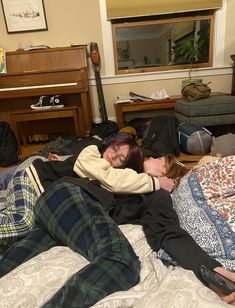 two people laying on a bed with their arms around each other and one person sleeping