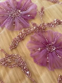 three purple flowers on a table with beads and sequins in the middle,