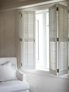 an open window with white shutters in front of it