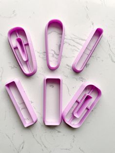 four pink kitchen utensils sitting on top of a white marble countertop next to each other