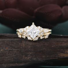 a gold ring with a princess cut diamond surrounded by three smaller round diamonds on top