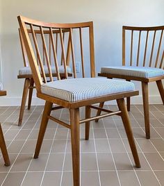 three wooden chairs with blue and white striped cushions on tiled flooring in an empty room