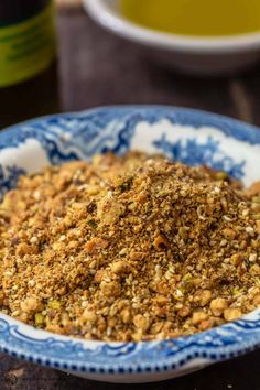 a blue and white bowl filled with granola on top of a table next to a bottle