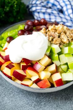 a bowl filled with apples, grapes, walnuts and yogurt sitting on top of a table