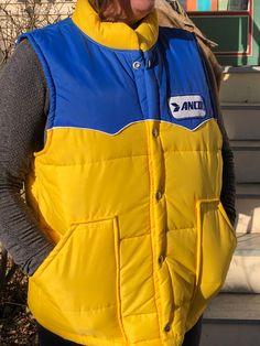 Vintage Anco Nylon Puffer Vest. From 1970's. Yellow and Blue with Anco patch. Size Large. Made in USA. Snap closures. Measures 24 inches from collar to hem. Measures 23 inches from pit to pit. Measures 9 inches shoulder to pit. Very clean but does have a couple of spots on collar. No rips, tears or stains. Gently worn. Please be aware USPS is experiencing shipping delays for the Holiday Season. Please order early to avoid shipping disruptions Vest Outfits, Yellow And Blue, Puffer Vest, Spot On, Puffer, Made In Usa, Holiday Season, Gender Neutral, Adult Outfits