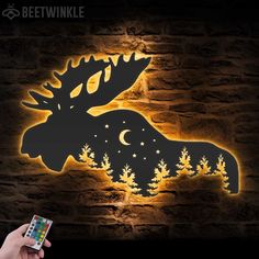 a person holding up a cell phone in front of a wall with a moose on it