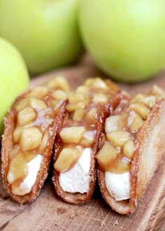 three pieces of food sitting on top of a wooden cutting board next to an apple