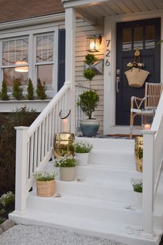 the front porch is decorated with potted plants and candles on the steps leading up to the door