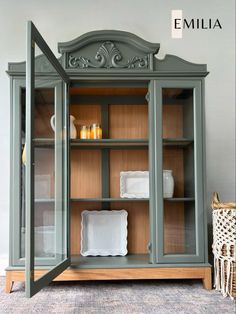 an old china cabinet with glass doors and wood trimmings, painted in gray