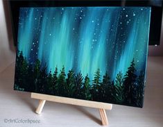 an acrylic painting of the aurora bore is shown on a wooden easel