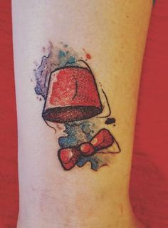 a small tattoo on the leg of a person with a red hat and bow tie