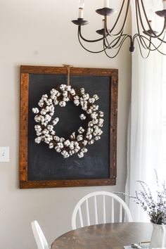 a chalkboard with a wreath hanging on the wall next to a chandelier