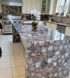 a large kitchen with white cabinets and marble counter tops, along with an island in the middle