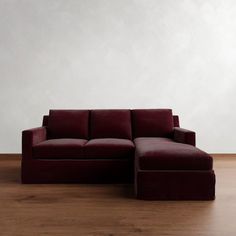 a red couch sitting on top of a hard wood floor next to a white wall