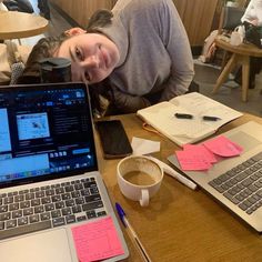 a woman sitting at a table in front of a laptop with sticky notes on it