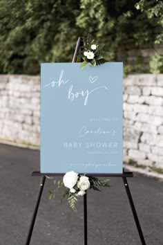 a welcome sign for a baby shower with white flowers on it and the words oh boy written in cursive font