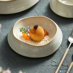 there is a small bowl with food in it on the table next to utensils