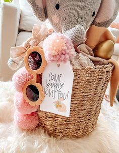 a stuffed elephant sitting next to a basket with sunglasses and a sign that says some bunny loves you