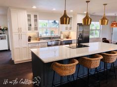 a large kitchen with an island in the middle and four stools at the end