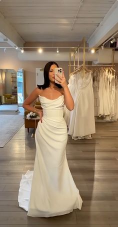 a woman taking a selfie in a wedding dress shop