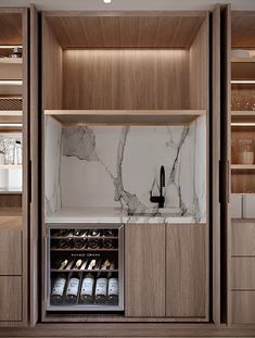 a kitchen with marble counter tops and wooden cabinets in the center, along with wine bottles on shelves