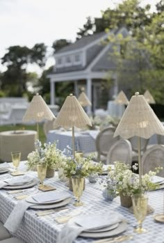 an outdoor table set up with place settings and flowers in vases on the table