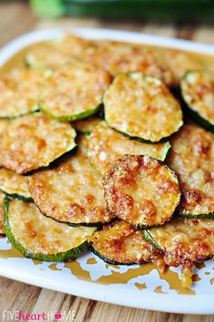 baked parmesan zucchini rounds on a plate with cucumbers in the background