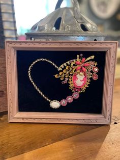 an ornate frame holds a necklace and brooche in the shape of a heart on display