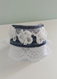 a white lace garter with flowers on it sitting on top of a table next to a wall