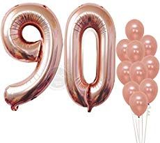 the number 90 is made out of pink foil balloons and stands in front of a white background