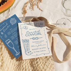 two wedding cards sitting on top of a table next to wine glasses and watermelon