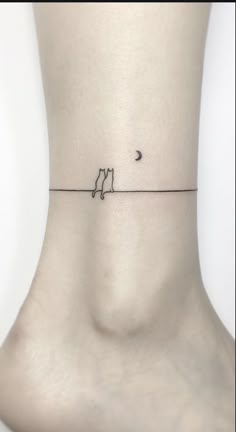 a small tattoo on the ankle of a woman's lower leg with a cat and moon