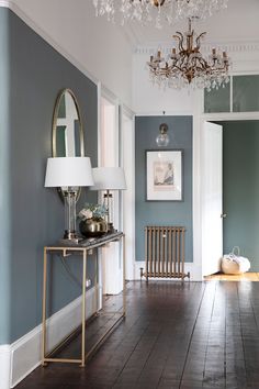 a room with blue walls and wood flooring in the center is lit by a chandelier