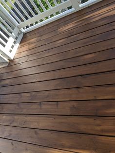 a wooden deck with white rails and railings on it's sides, looking down at the ground