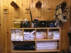 a shelf filled with lots of towels and other items next to a wall mounted coat rack