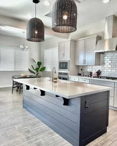 a large kitchen with an island in the middle and two pendant lights hanging from the ceiling