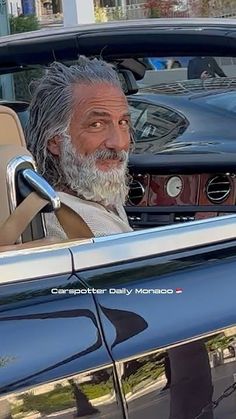 an old man sitting in the drivers seat of a car