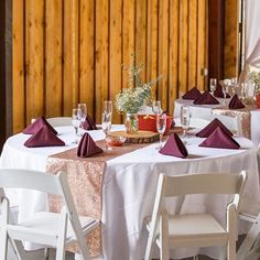 the table is set with white chairs and red napkins