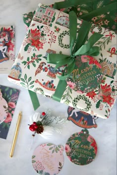 a present wrapped in wrapping paper and tied with a green ribbon, surrounded by other christmas decorations