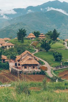 a small village on top of a hill surrounded by mountains and greenery with houses in the distance